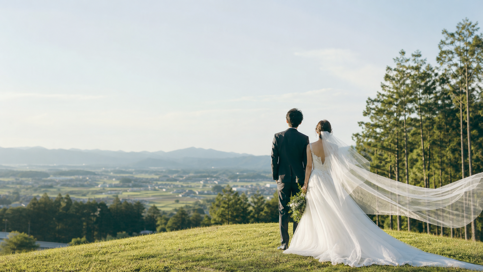 高台から景色を見つめる新郎新婦の後ろ姿